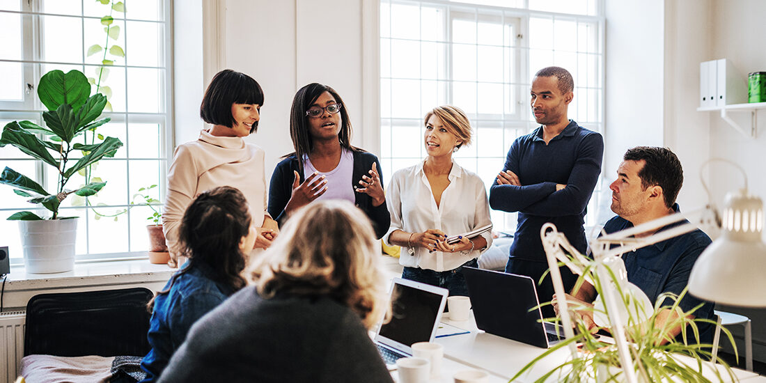 Sju personer i ett ljust arkitektritat kontor deltar i ett effektivt och kreativt möte