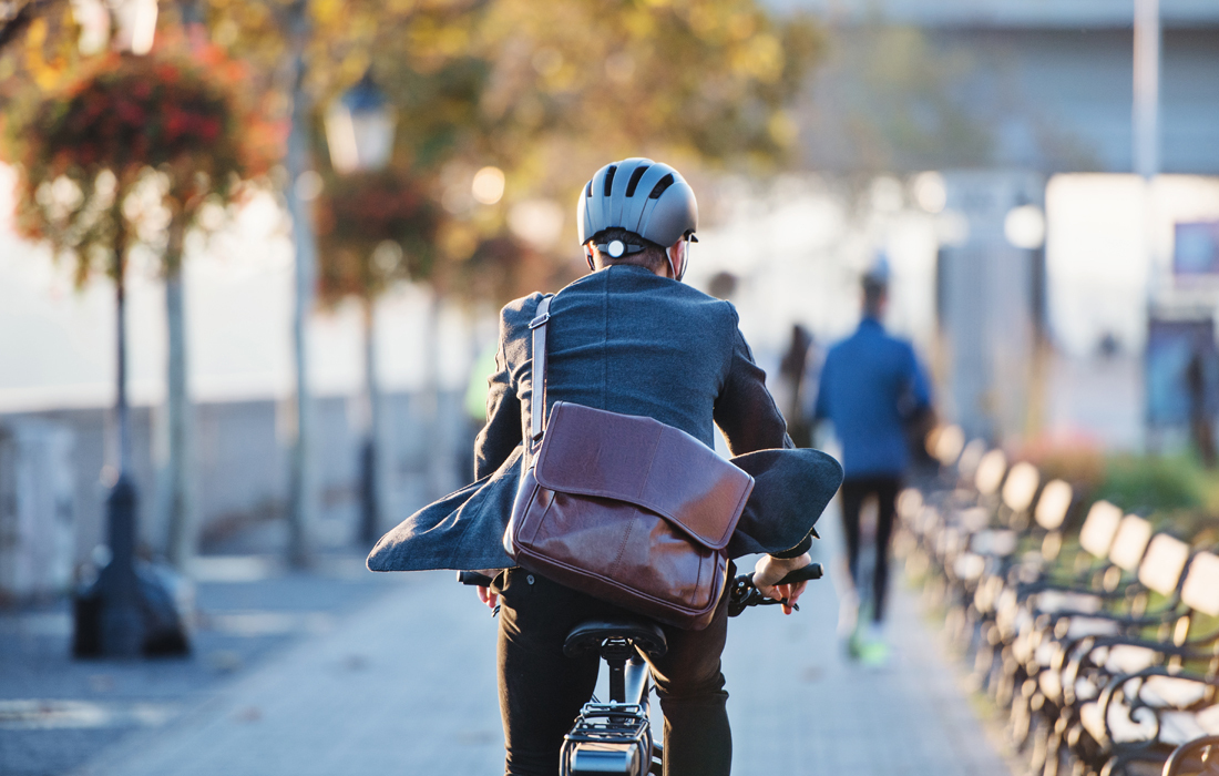 En cykelpendlande man i kavaj och hjälm i urban miljö på väg till jobbet.